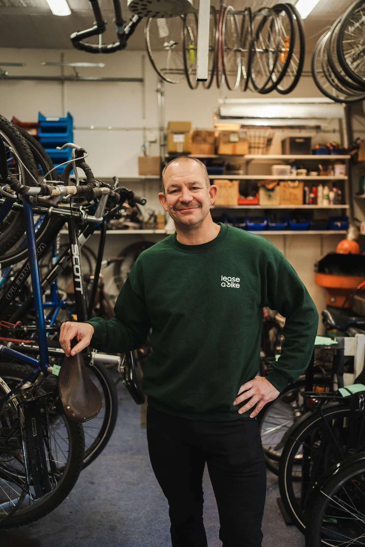 Man with Kalkhoff bike is standing in front of dark wall.