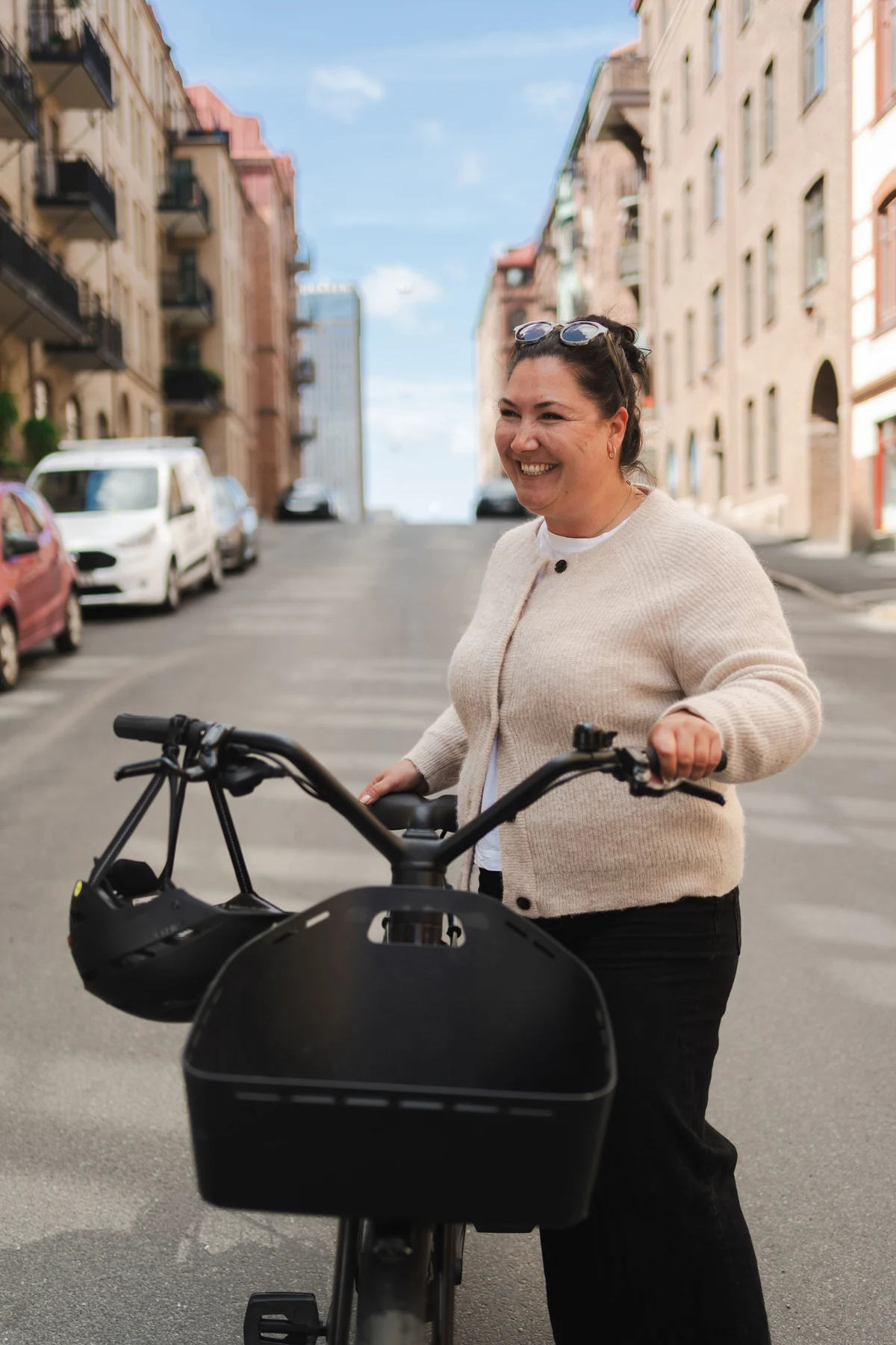 Glad kvinna med elcykel i stan